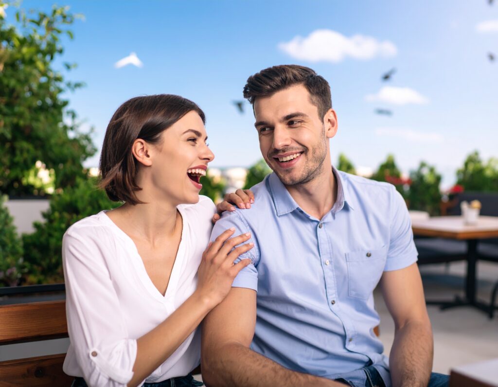 Un couple souriant assis ensemble à l’extérieur d’un café